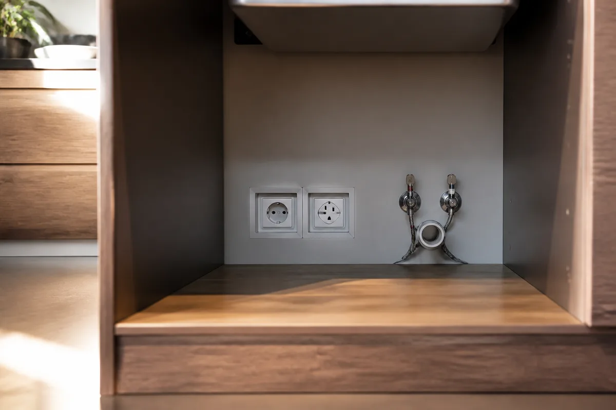 Prises et arrivée d&rsquo;eau positionnées au fond d&rsquo;un caisson de cuisine
